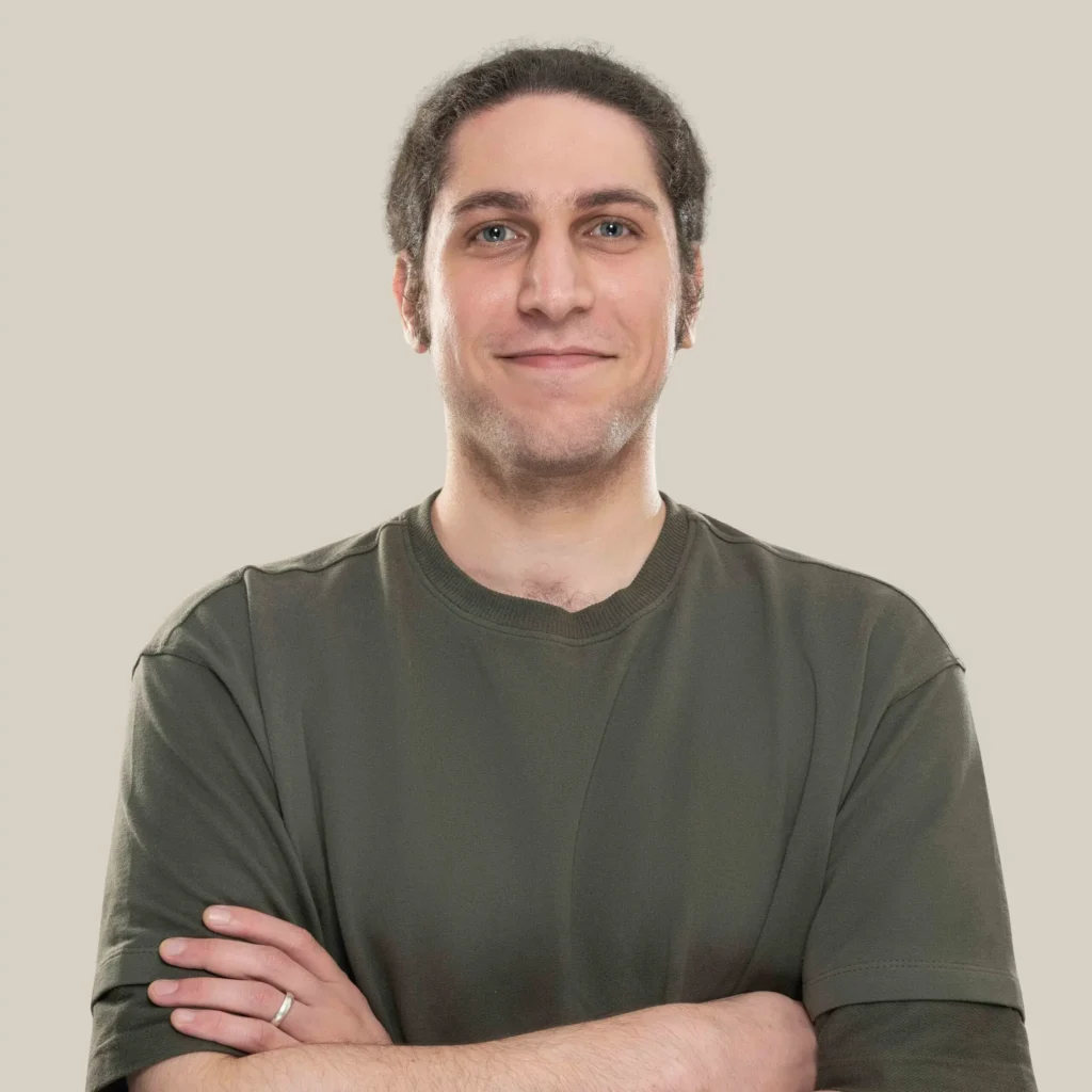 تصویر عرفان پارسا زاده کارشناس ارشد سئو وی دیجیتال مارکتینگ که با لباس سبز رنگ دست به سینه ایستاده و داره لبخند میزنه