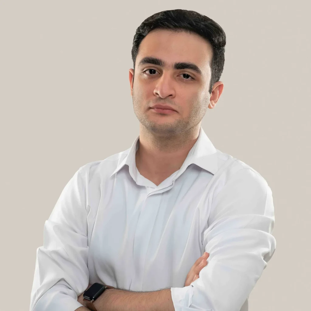 تصویر وحید طلائی کارشناس ارشد گوگل ادز وی دیجی که پیرهن سفید پوشیده و دست به سینه کمی مایل به سمت چپ ما ایستاده